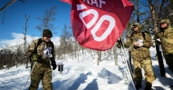 The RAF100 flag is waved at the finish line of the cross-country skiing race held on the final day of Ex-WINTERMARCH as one of the skiers crosses the line. Pic: SAC Lloyd Horgan.